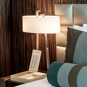 Oval table lampshade A white oval lampshade shown on a modern silver table lamp next to a bed