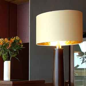 A cream drum lampshade on wooden standard lamp