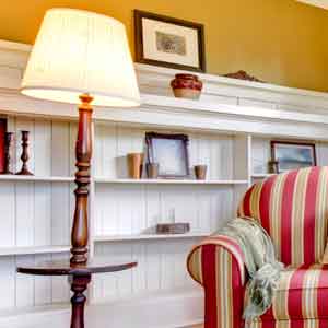 Ribbon Pleat Empire A cream pleated lampshade shown on a brown floor lamp