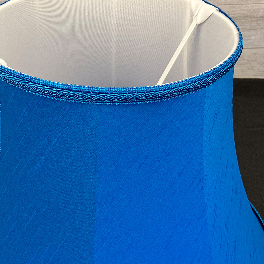 Close up image of a Traditional Bright Blue Faux Silk Lampshade with a matching Plait Trim, showing the inside soft white lining