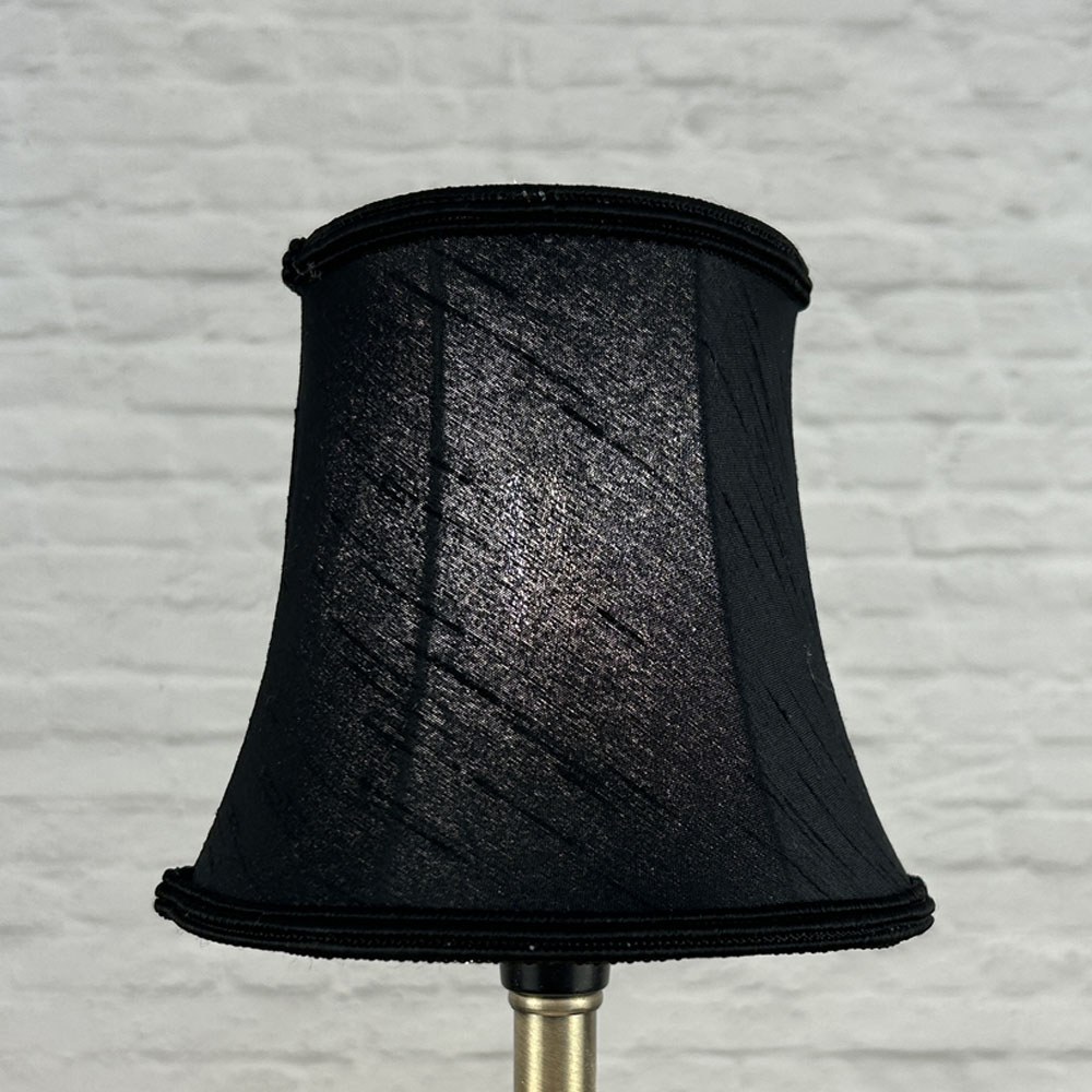 Black bowed chandelier shade in faux silk lit showing warm glow and matching soutache trim