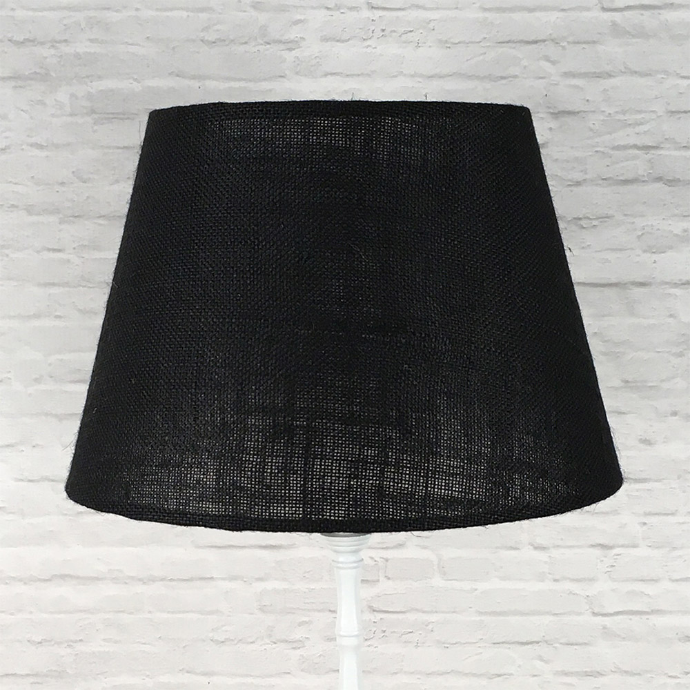 Black hessian tapered drum lampshade fitted to a white standard floor lamp