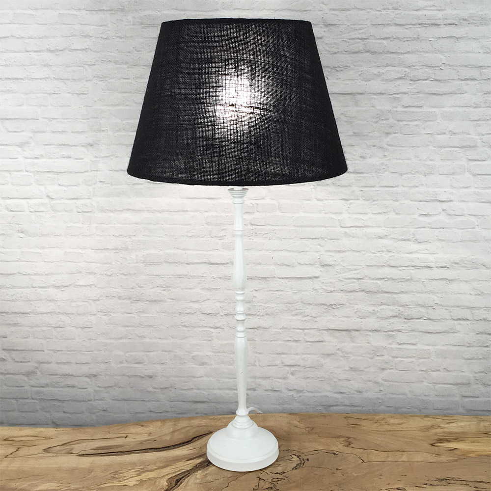 Black hessian tapered drum lampshade lit on a white table lamp base