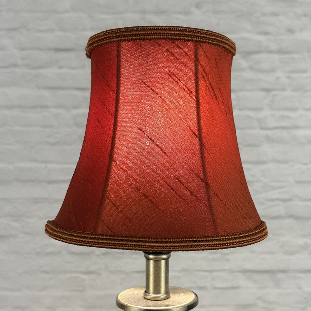 Terracotta bowed chandelier shade in faux silk lit showing warm earthy tone and soutache trim