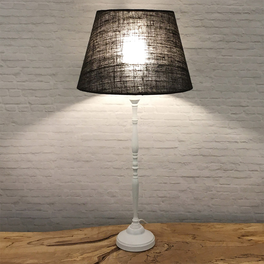 Brown hessian tapered drum lampshade lit on a white table lamp base