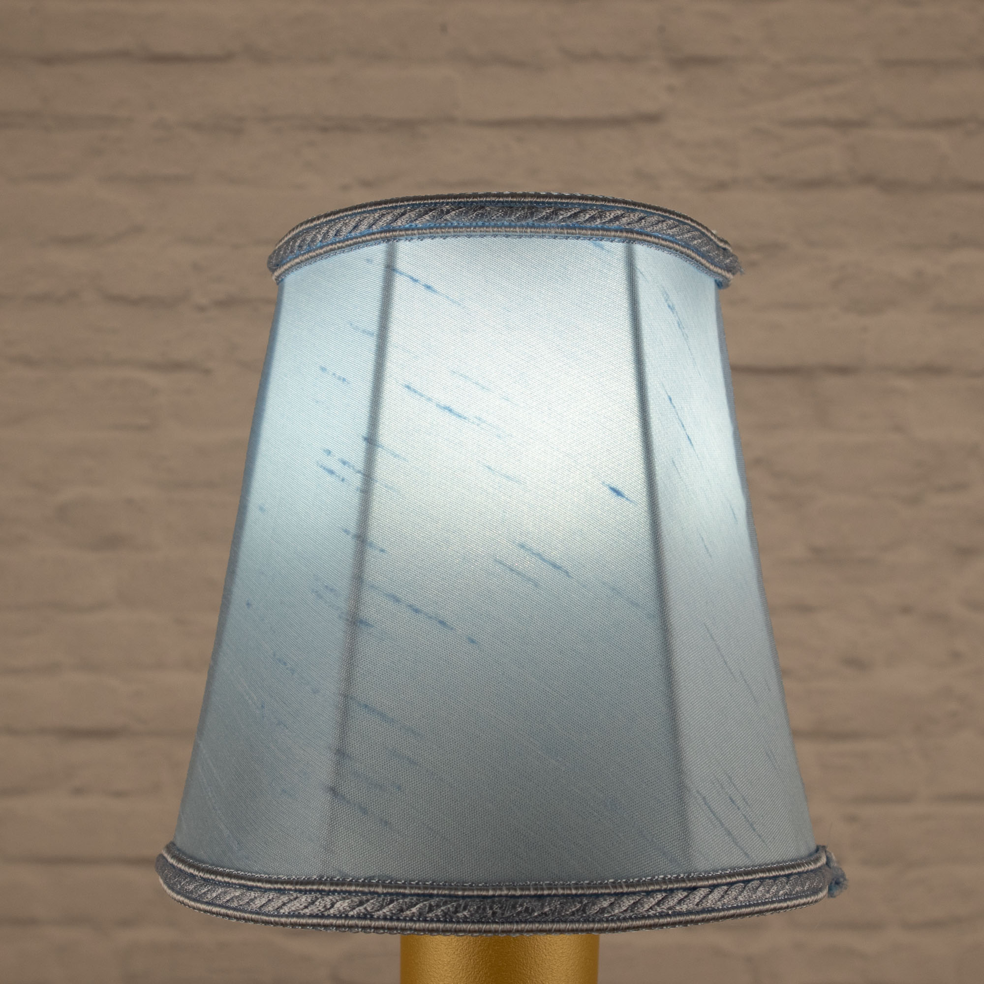 Lit pale blue empire faux silk chandelier shade with matching rope trim