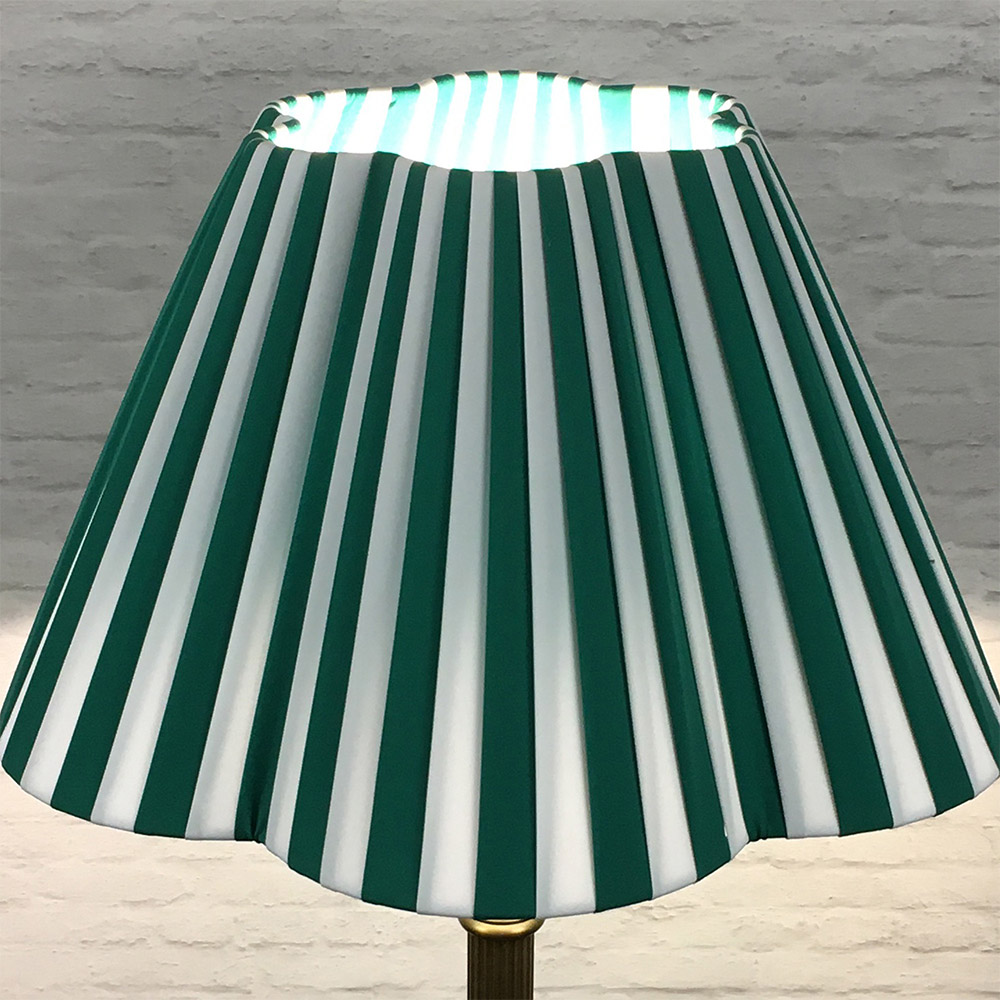 Green and white striped pleated lampshade illuminated with a soft glow