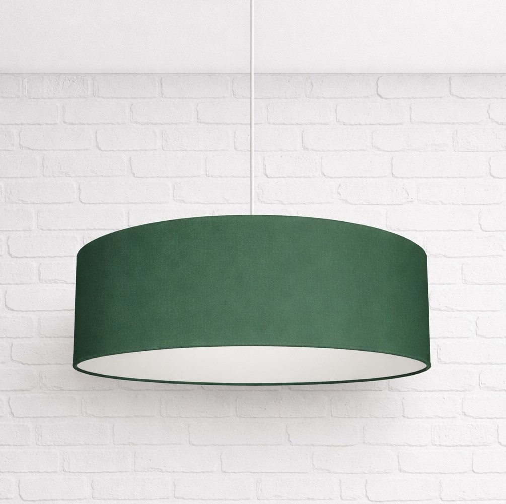 Dark Green drum pendant lampshade hanging from white ceiling against white brick wall