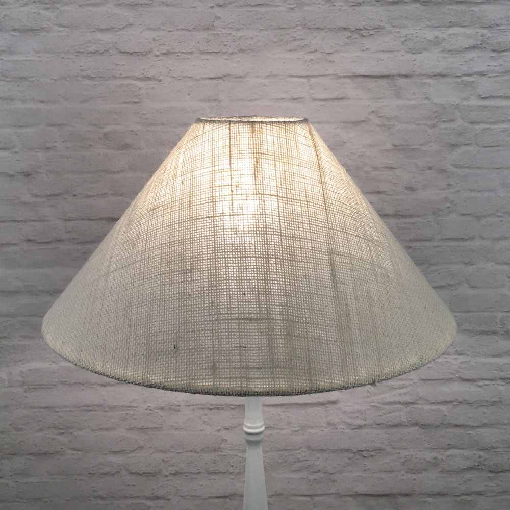 Off-white hessian coolie on a standing lampshade lit