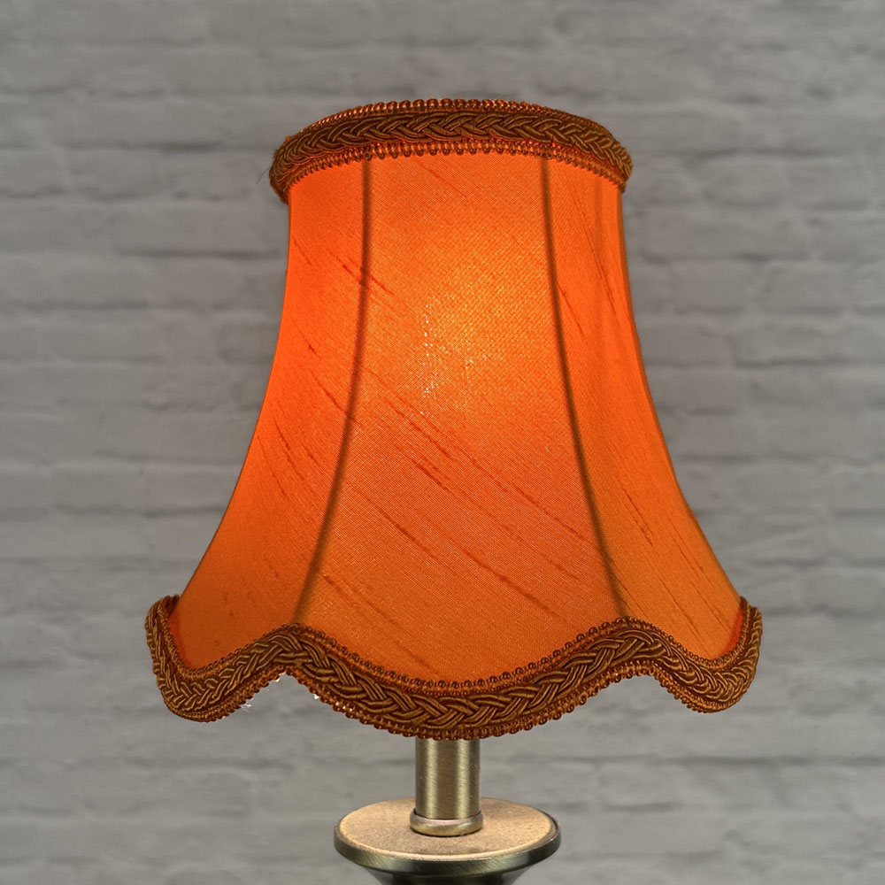 Pumpkin scalloped chandelier shade in faux silk lit showing warm orange tone and plait trim