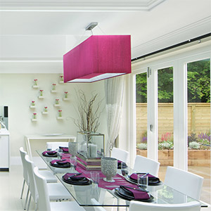 A hot pink pendant light shade above a kitchen table