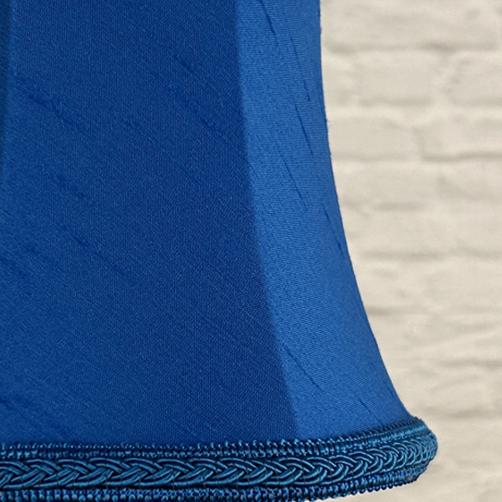 Close-up of blue faux silk bowed chandelier shade with plait trim