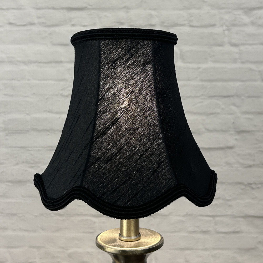 Black scalloped chandelier shade in faux silk lit to show warm glow and soutache trim