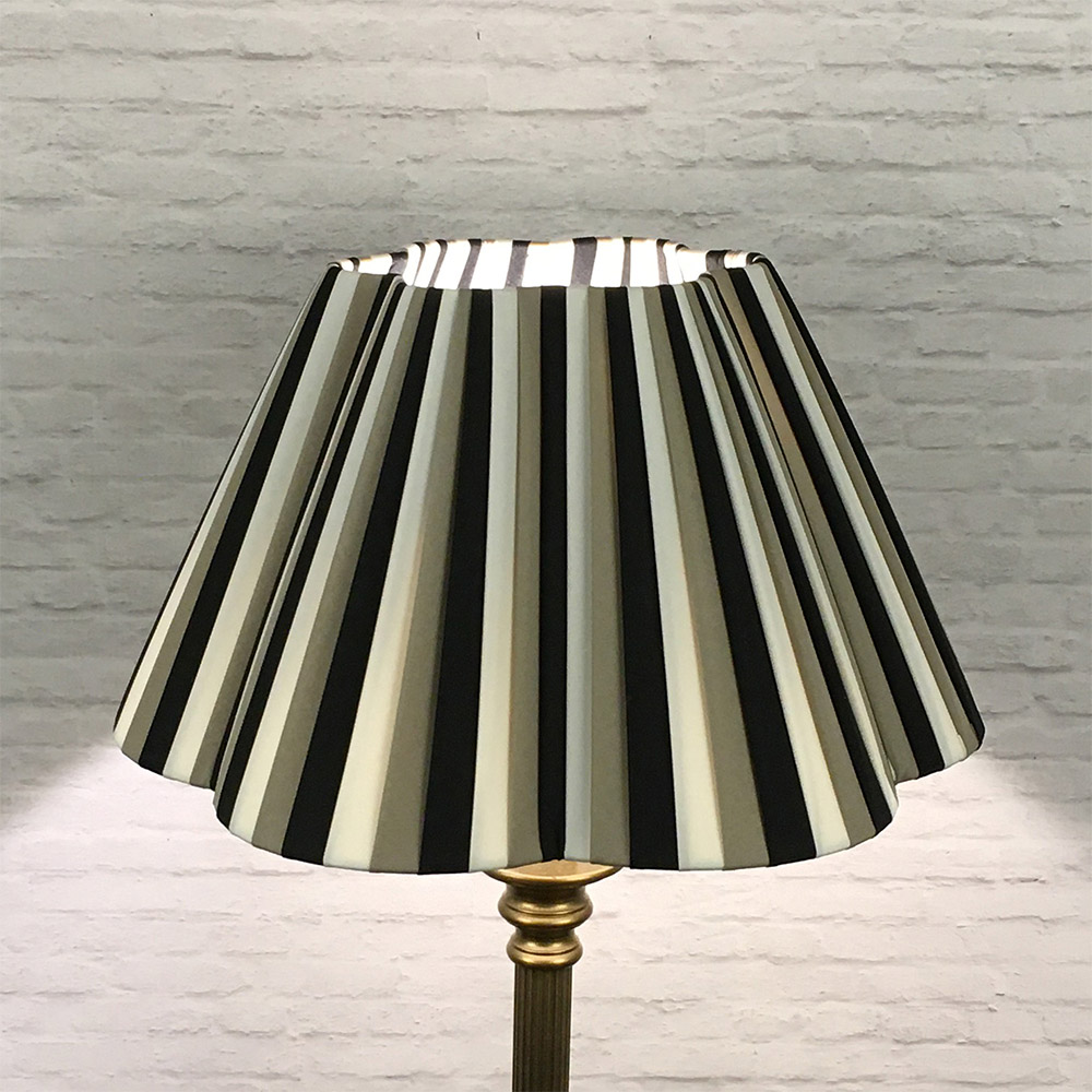 Triple colour striped pleated lampshade illuminated with a warm glow