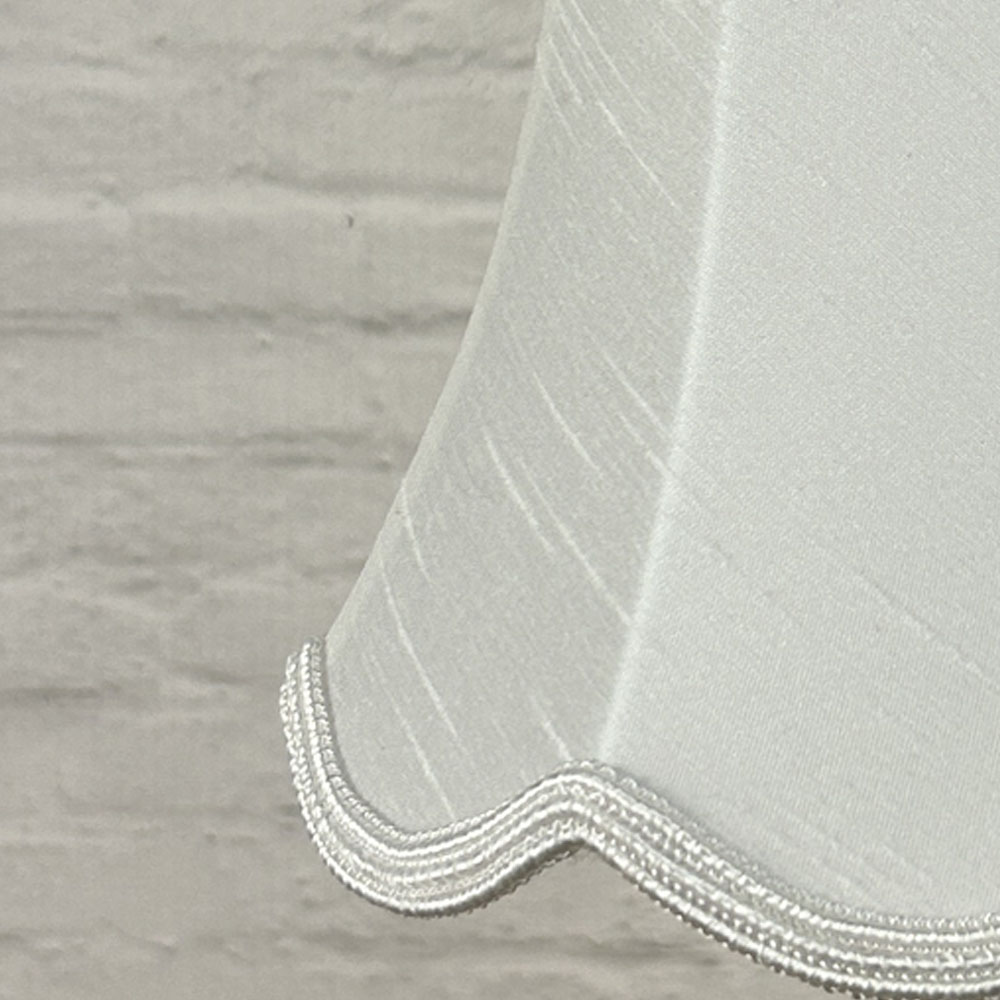Close-up of white faux silk scalloped chandelier shade with matching white soutache trim