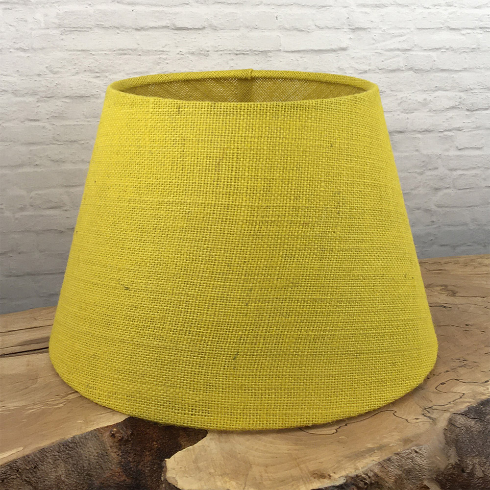 Yellow hessian tapered drum lampshade on wooden surface