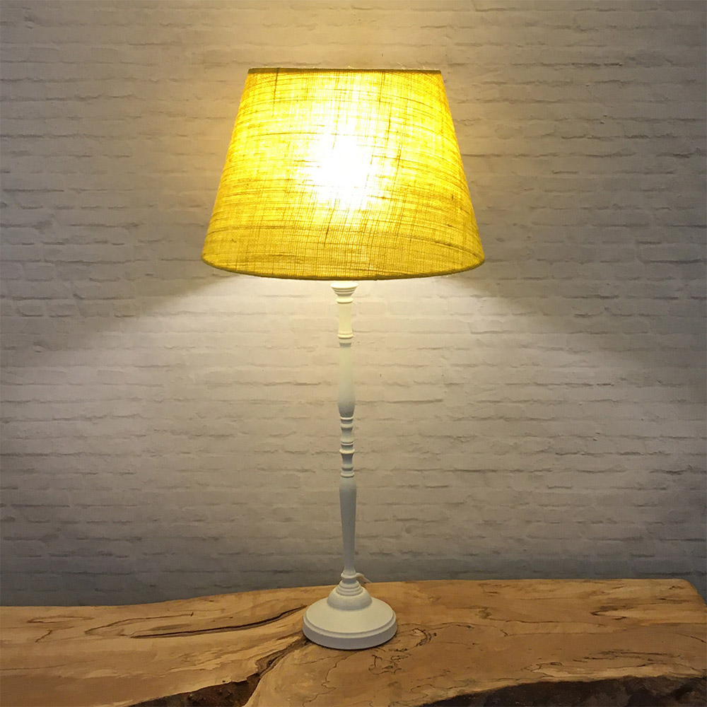 Lit yellow hessian lampshade on table lamp in low light